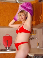 Mature blonde plays with her shaved pussy in the kitchen